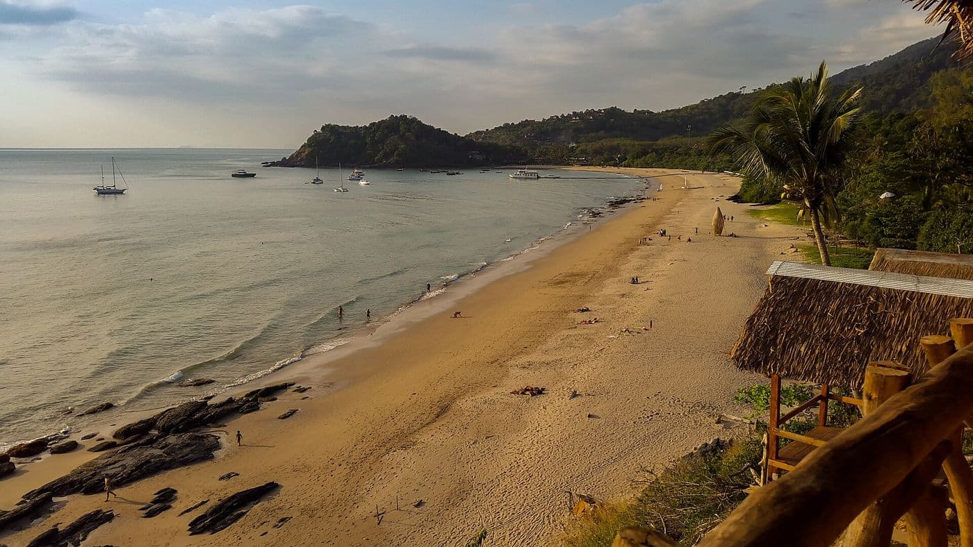 Panorama of Kantiang Beach curving toward a forested headland, with small boats in the water